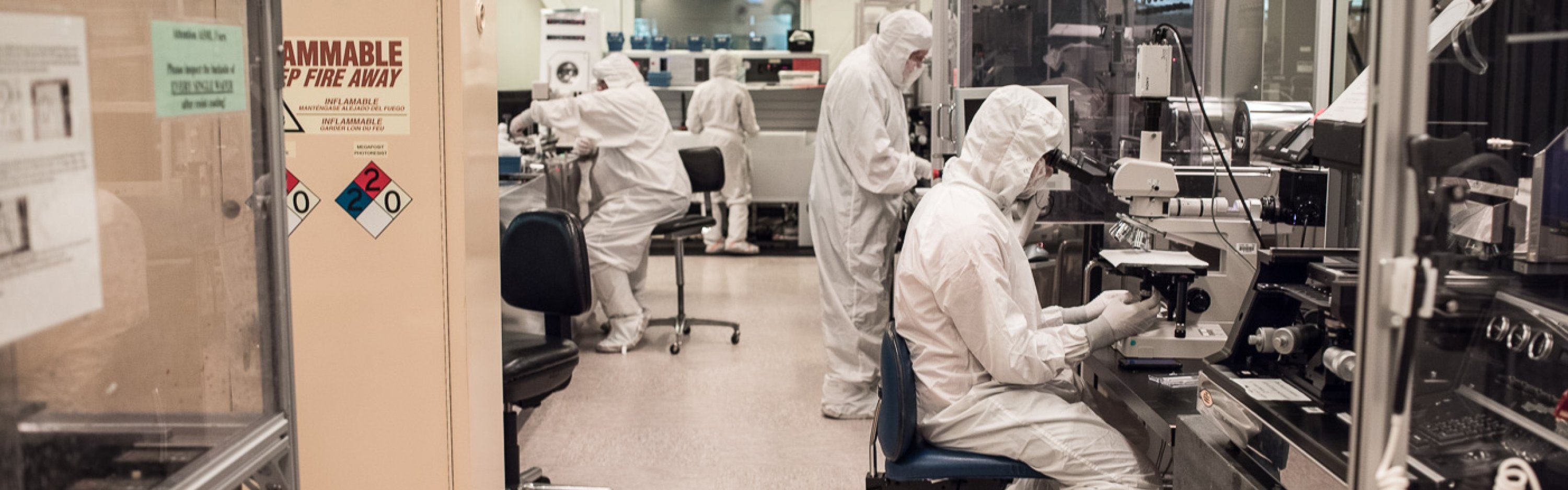 Students in white suits sitting at machines in a lab