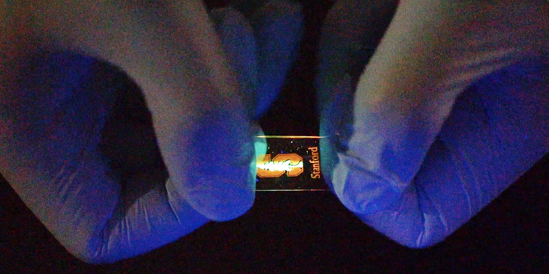 Hands holding a light-emitting, stretchable polymer.