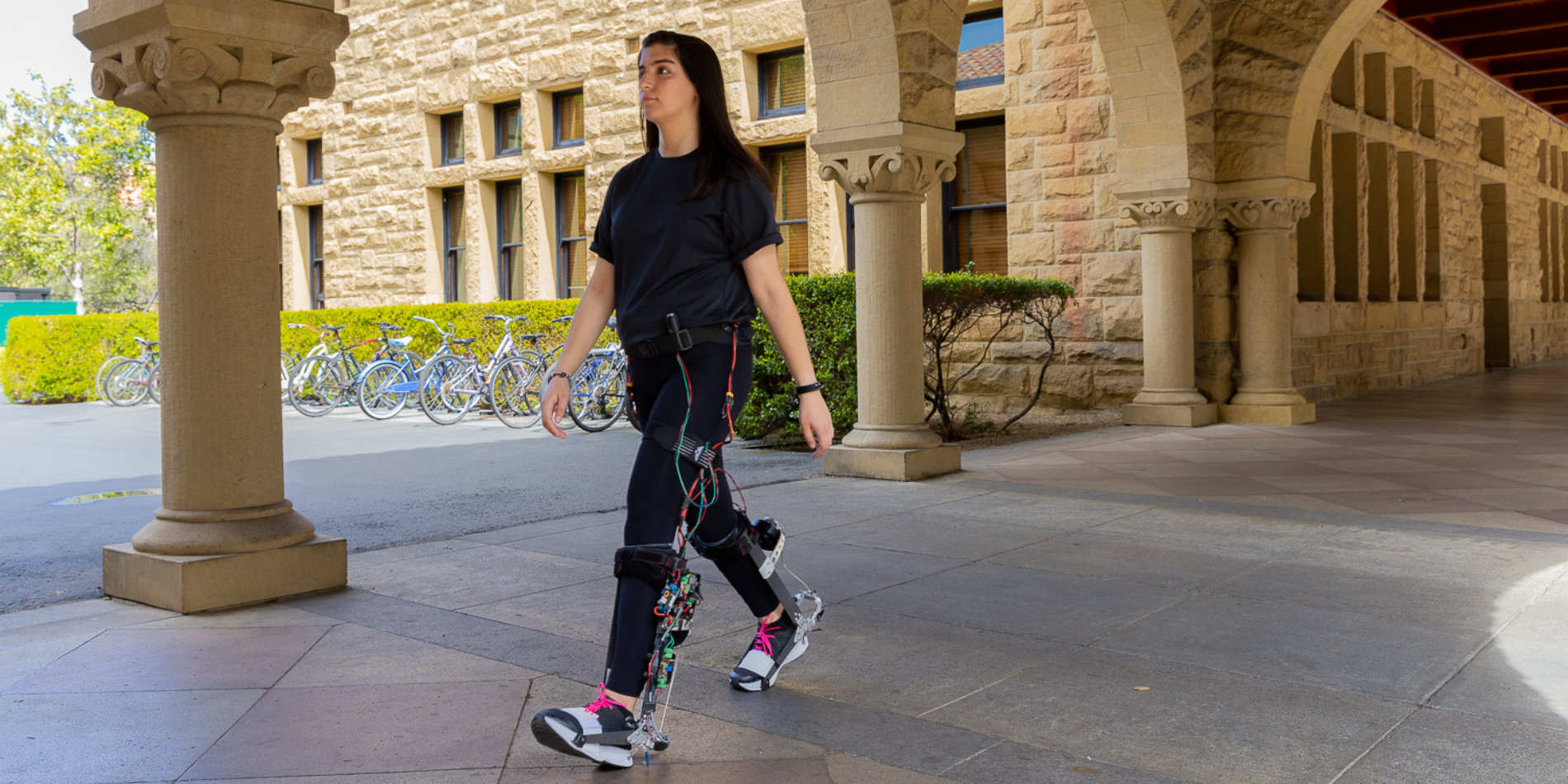 A person walking on campus while wearing the exoskeleton boots. 