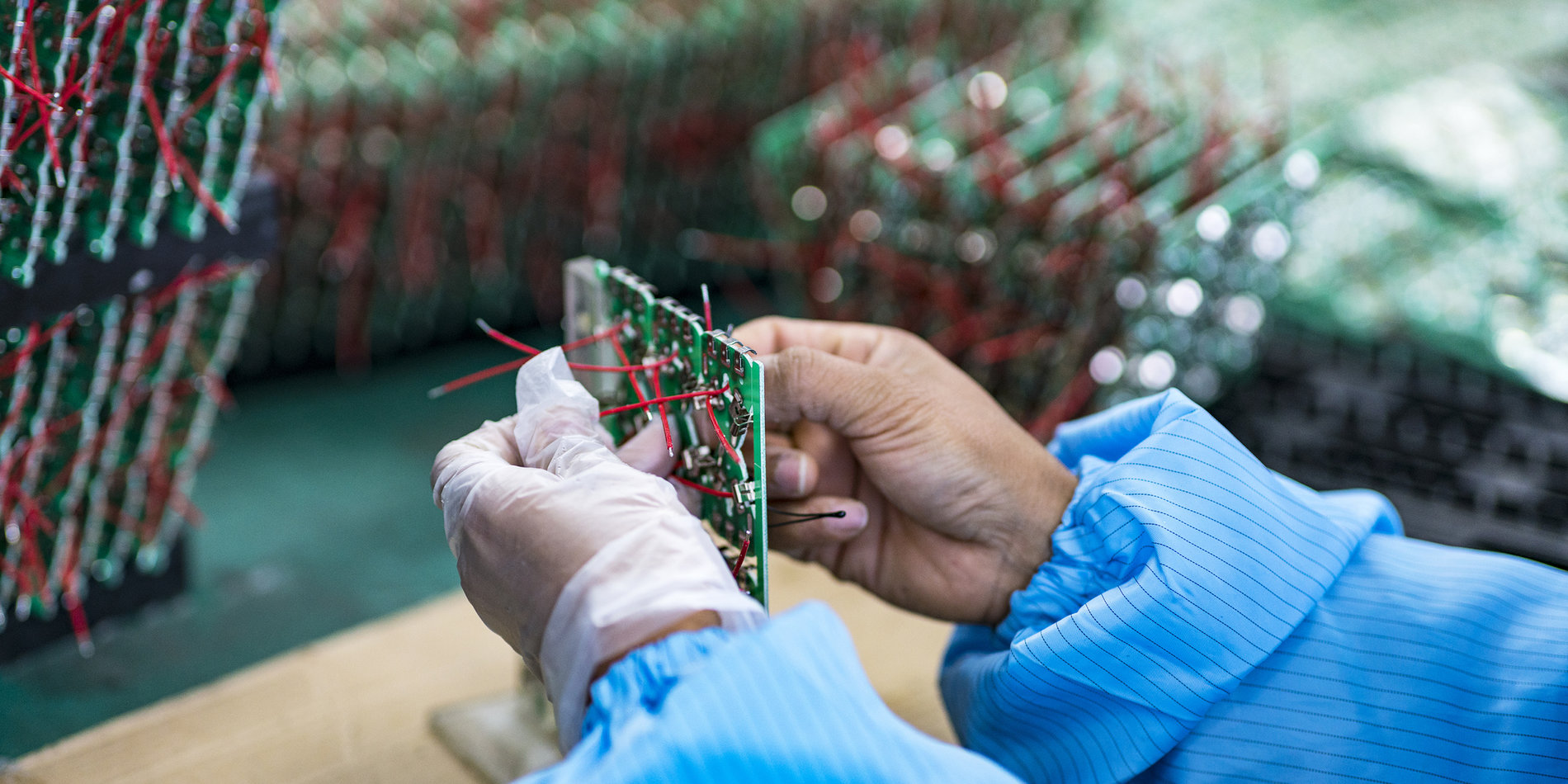 Worker in factory assembling a circuit board.