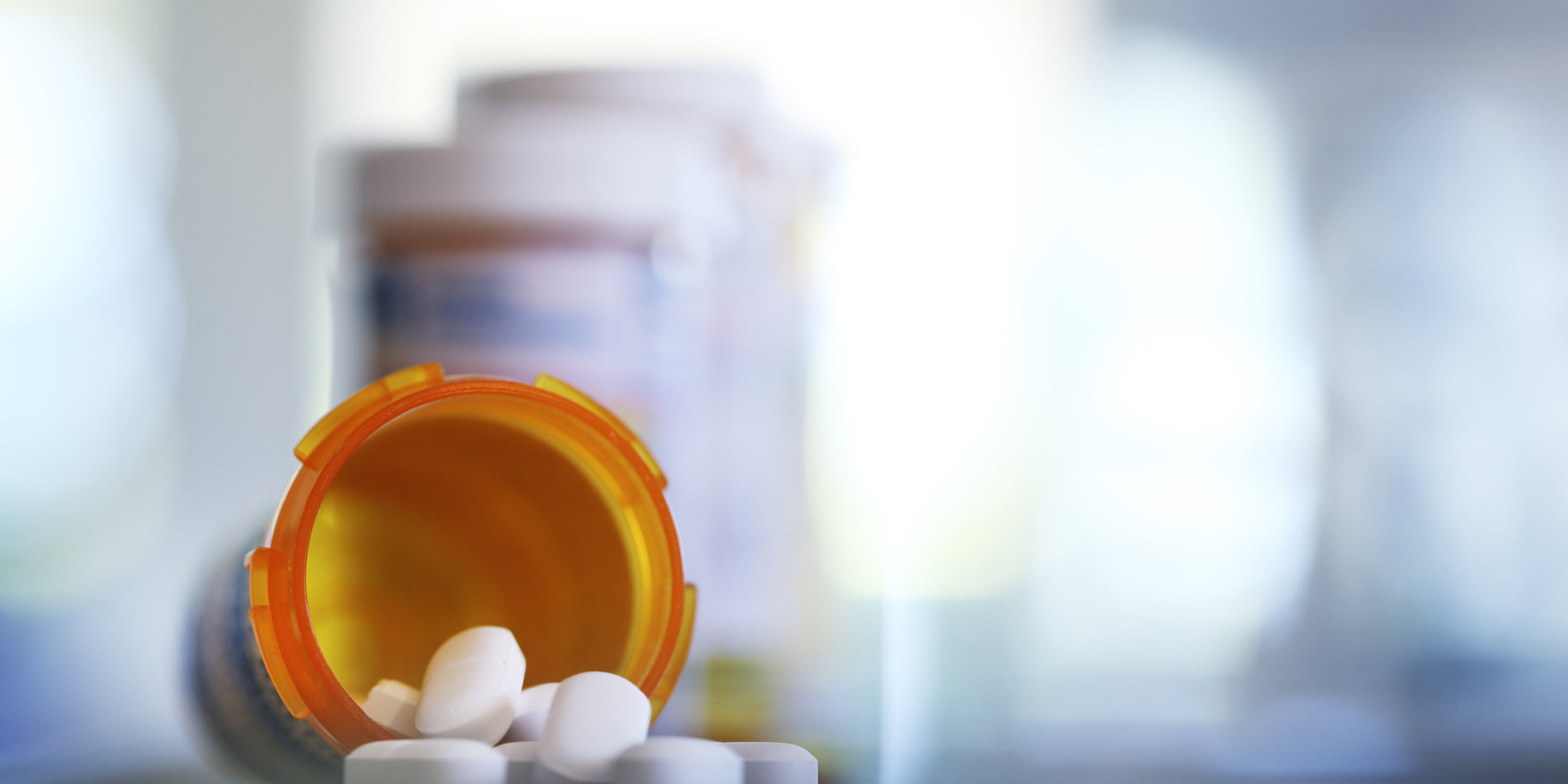 Pills pour out of prescription medication bottle onto a countertop