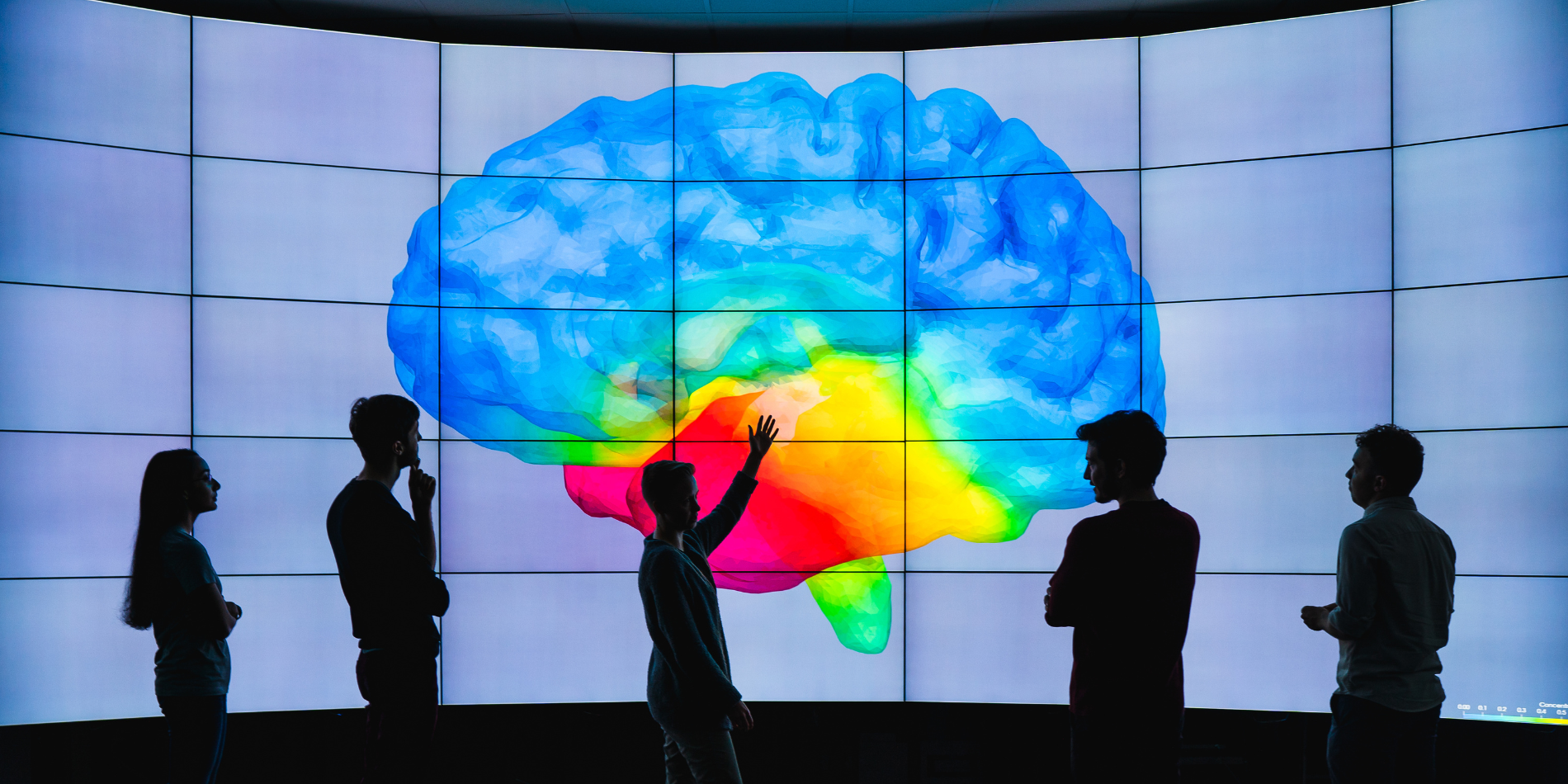 A group of researchers standing in front of a large image of a brain.