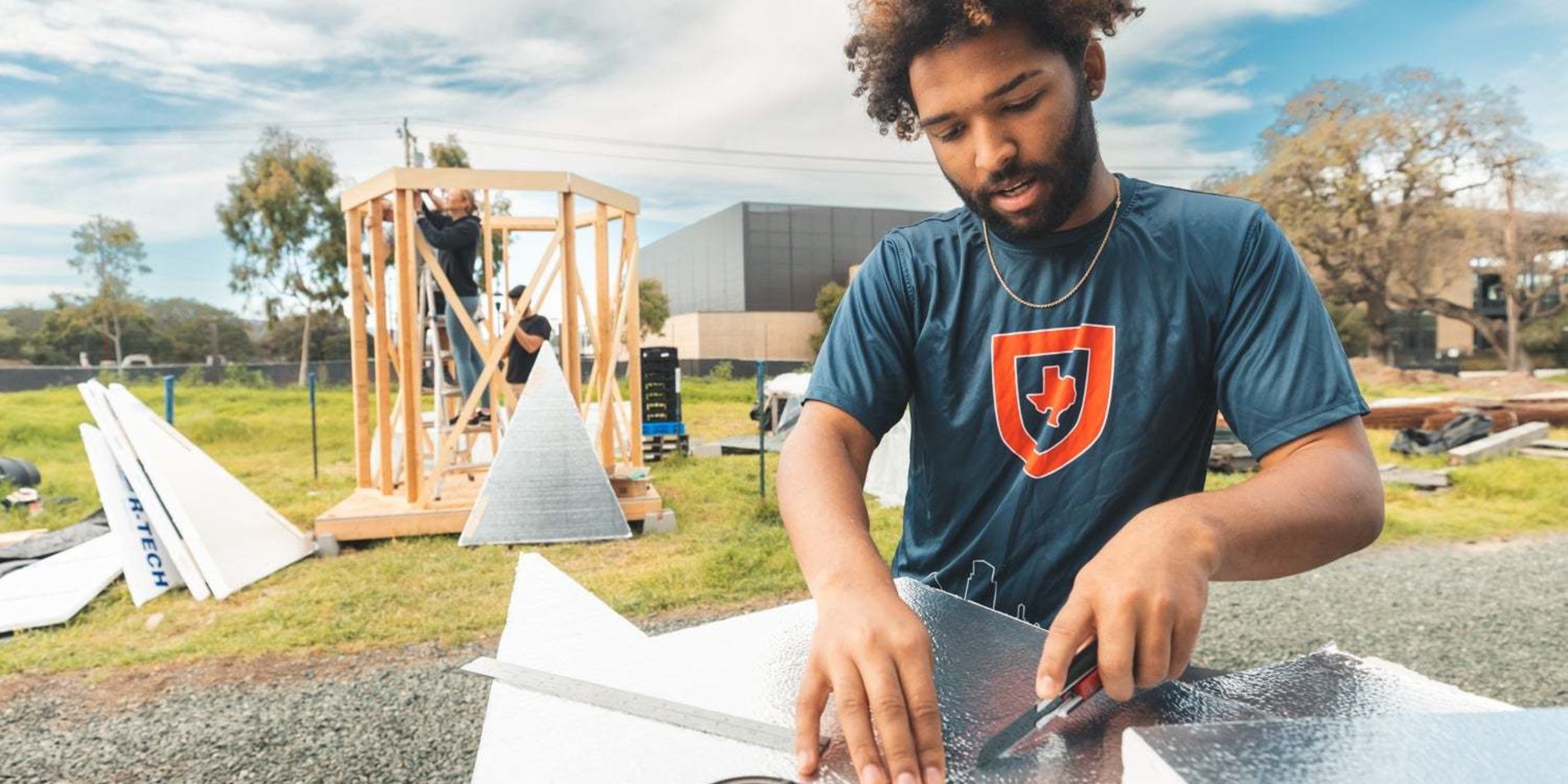 A student cutting foam board outside for a building project