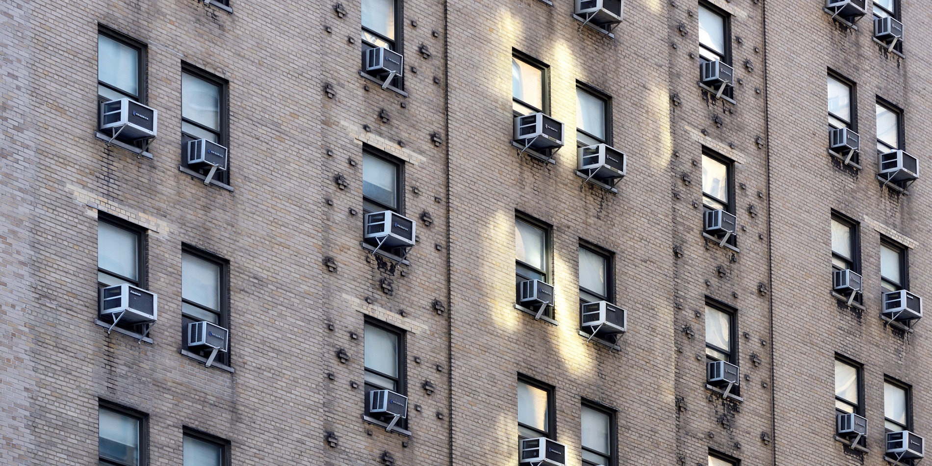 Image of a building with air condition units hanging from the windows.