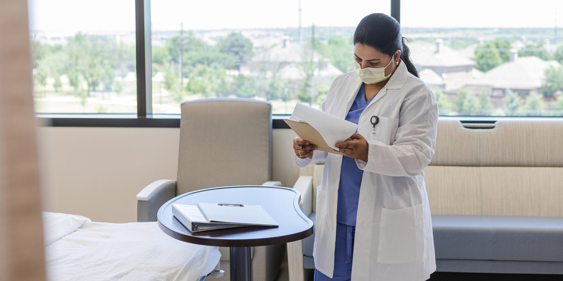 Photo of a doctor reviewing patient records in a hospital room.