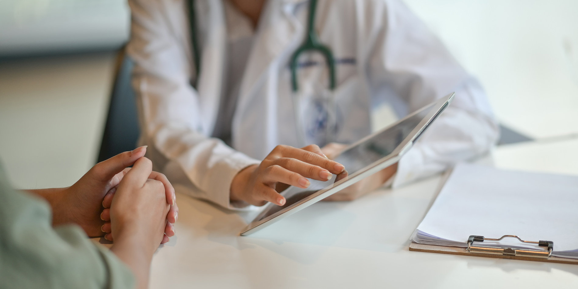 Image of a doctor showing a patient something on a digital tablet.