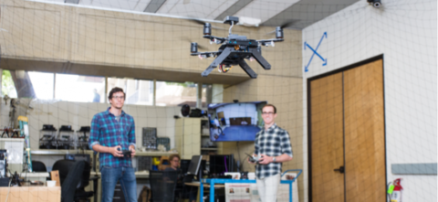Drone hovering in front of two students in lab