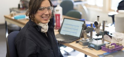Woman looking up from a lab setting with laptop