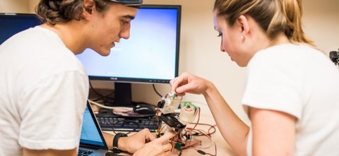 Two students working on electronics with wires