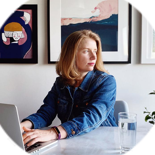 Sarah Fletcher sits at a laptop while looking over her shoulder towards a window