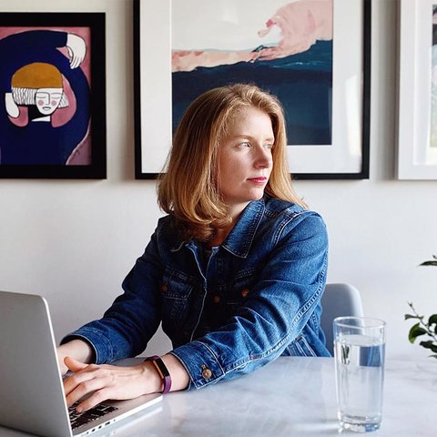 Sarah Fletcher sits at a laptop while looking over her shoulder towards a window