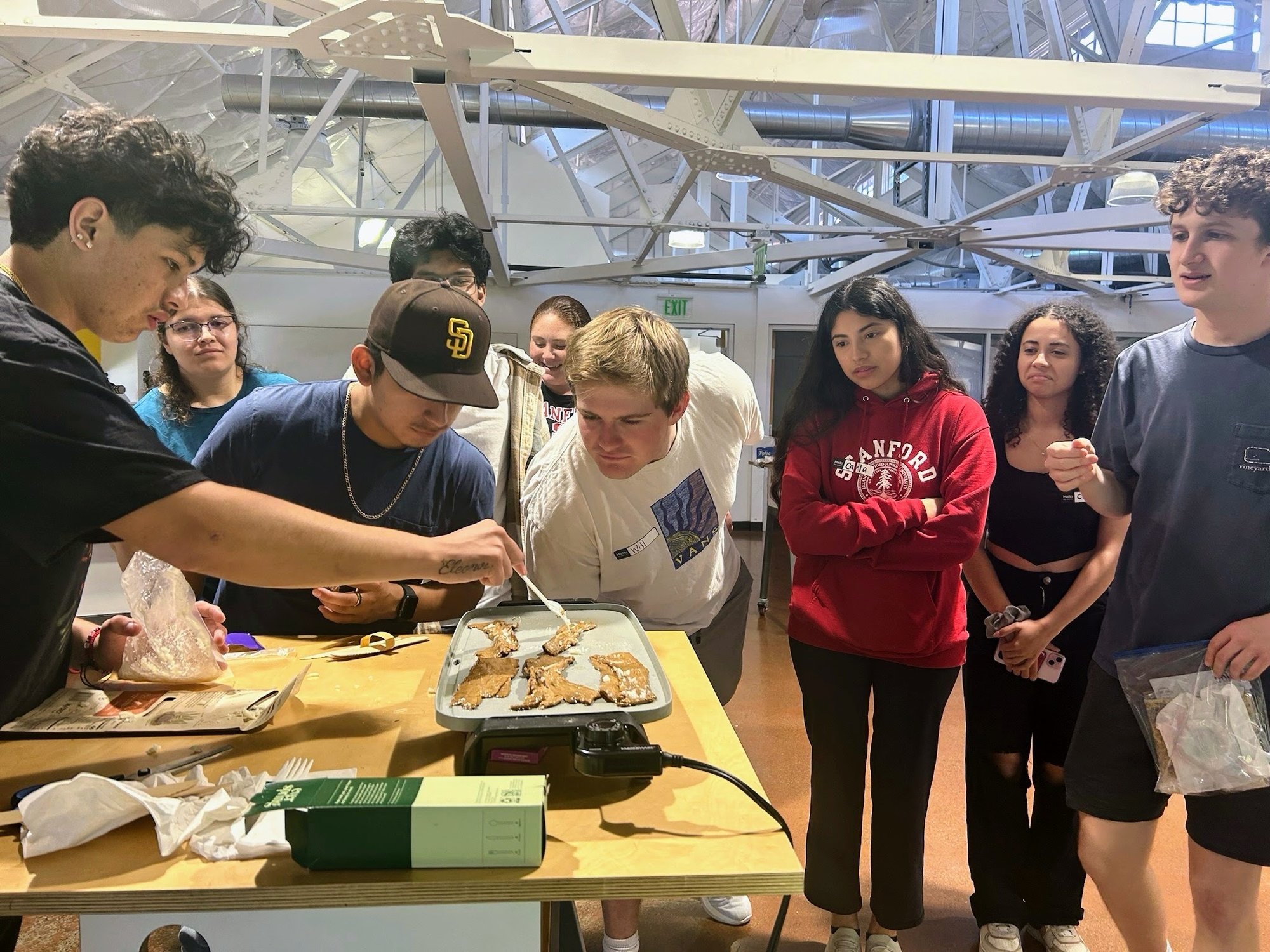 Students gathered around a table to taste mycelium (mushroom) bacon.